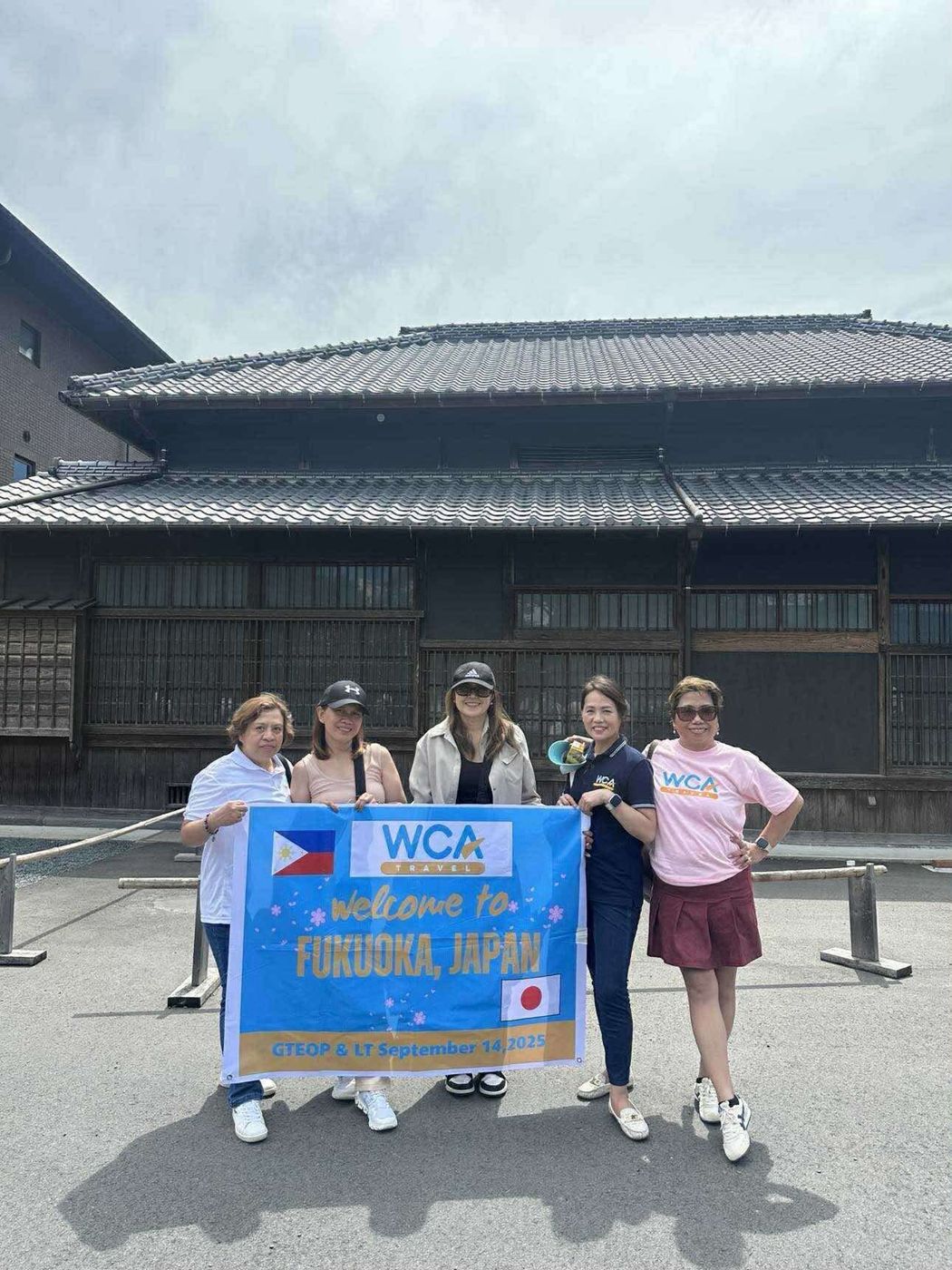 Team members with a WCA welcome banner in Fukuoka, Japan